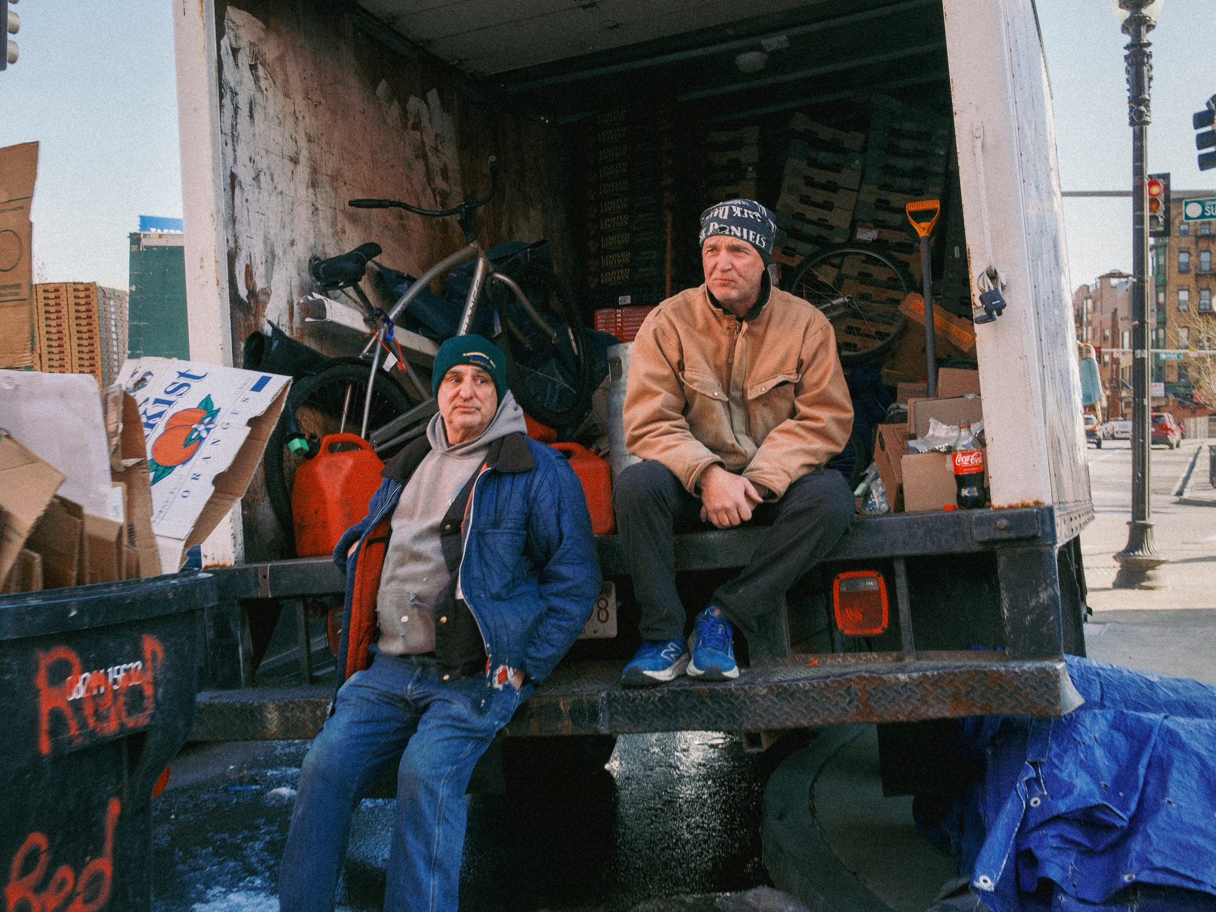 Two vendors resting by a truck on a Boston street